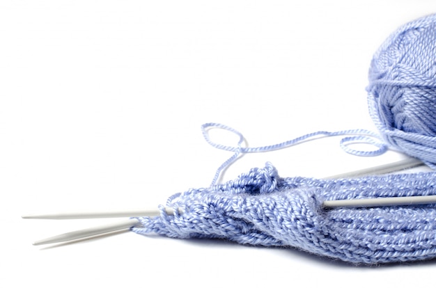 Balls of blue yarn and knitting needles. White background. Copy space.