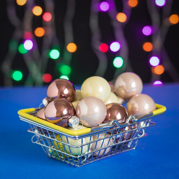 Balls for a christmas tree in an iron basket on a surface of colorful lights