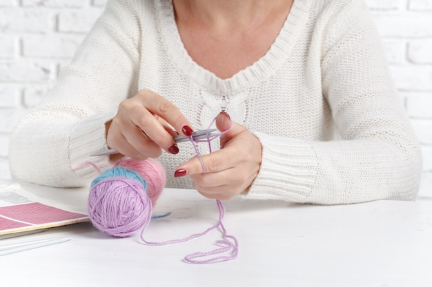 Balls of colored yarn. Sample knit. Women's hands are knitted