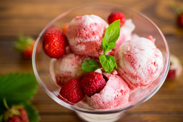 Balls of homemade strawberry ice cream in a bowl on a wooden table