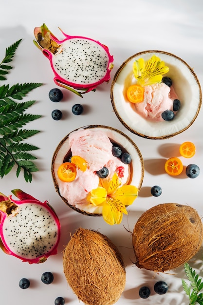 balls of ice cream decoration flowers and berries in halves of coconut with green leaves