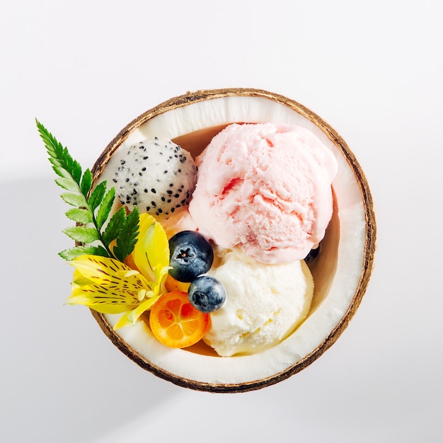 Palline di gelato decorazione fiori a metà di cocco. concetto tropicale estivo.