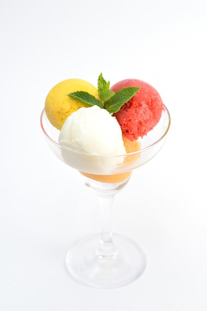 Balls of ice cream with mint in a transparent glass, on white