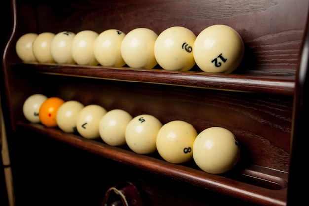 Balls for pool billiards on the shelf , billiard balls for American billiards , balls for Russian billiards , colored or white balls for billiards on a wooden background. Close-up photo. Soft focus.