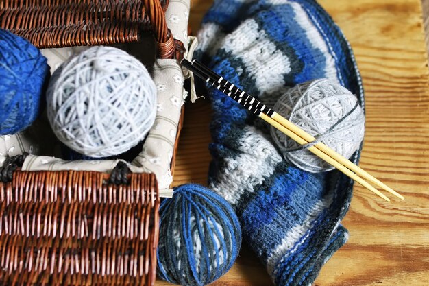 Balls of wool and knitting needles on a wood background