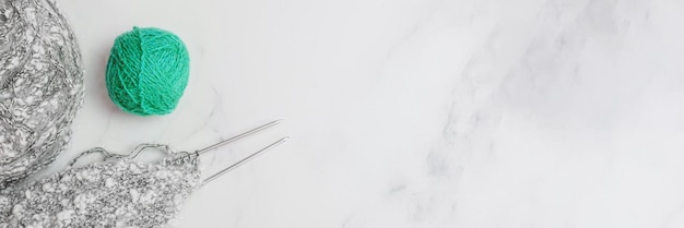 Balls of woolen thread and long metal needles on on light background