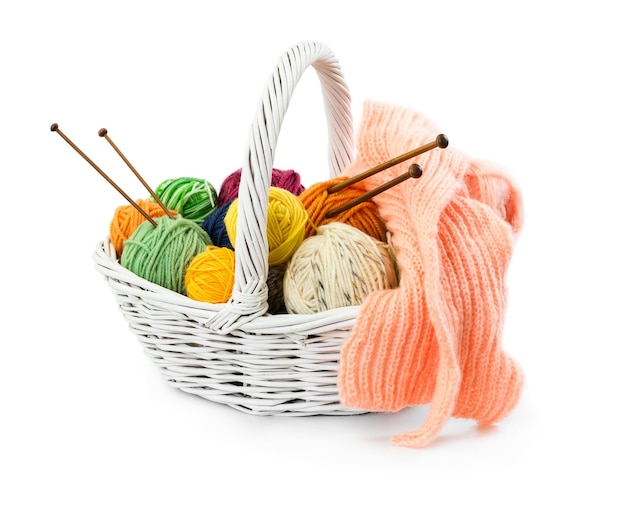 Balls of woolen threads for knitting in wicker basket isolated on white background