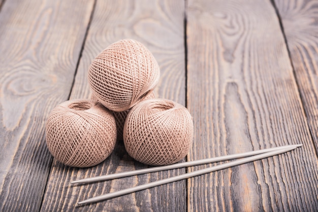 Balls of yarn and knitting needles for knitting on a wooden background.