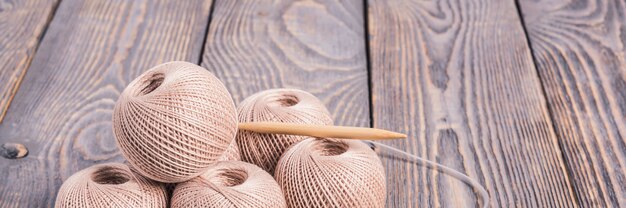 Balls of yarn and knitting needles for knitting on wooden.