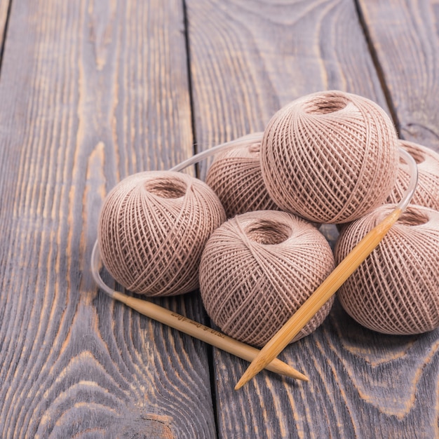 Balls of yarn and knitting needles for knitting on wooden.