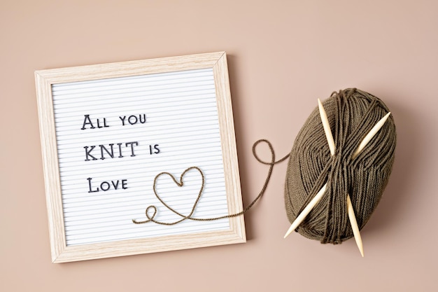 Balls of yarn and letter board with text All you knit is love.