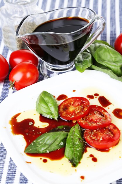 Balsamic vinegar tomato and basil on table closeup