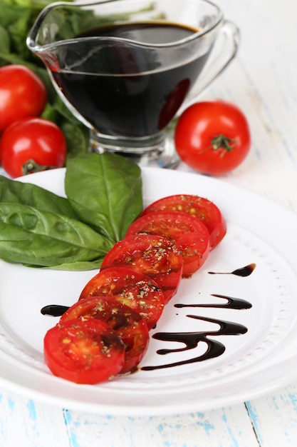 Foto tomato con aceto balsamico e basilico in tavola