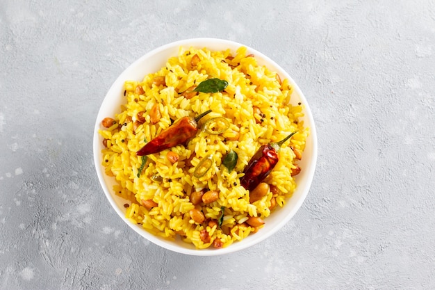 A balti dish with lemon rice, rice flavoured with mustard\
seeds, curry leaves and green chili in a white bowl