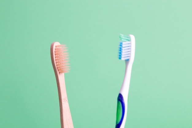 Bamboe en plastic tandenborstels op een groene achtergrond nul afval levensstijl concept