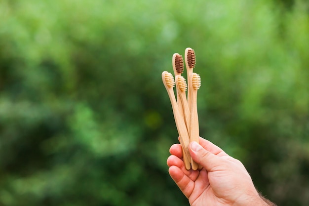 Bamboe tandenborstels in een hand. Natuurlijke achtergrond met kopieerruimte