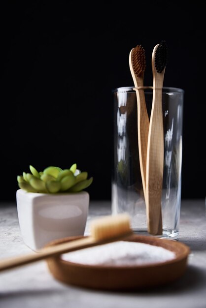 Bamboes tandenborstels in glazen bakpoeder en badkamerhanddoeken op een donkere achtergrond