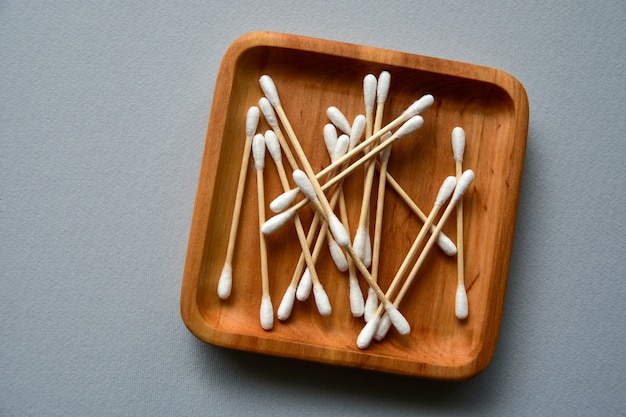 Photo bamboo cotton swabs on a wooden plate. gray paper surface. zero waste concept. view from above. copy space.