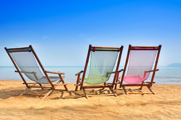 밝은 태양과 파도가 있는 모래사장에 있는 대나무 데크 의자 태국 남쪽 섬 해변에서 편안한 하루