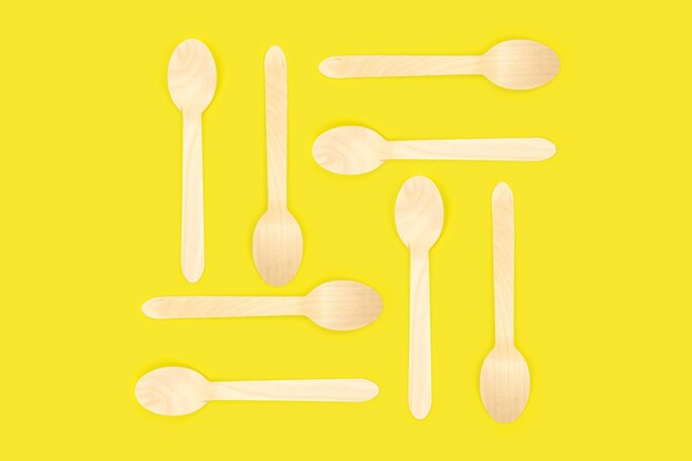 Bamboo disposable picnic spoons on a yellow background. eco conservation concept