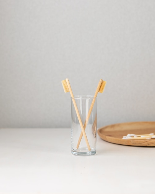 Bamboo ecofriendly toothbrushes stand in a glass on a white table