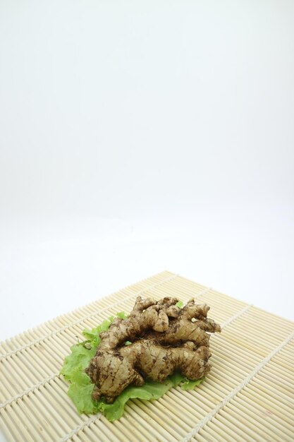 Photo a bamboo mat with a green leaf on it and a ginger on top.