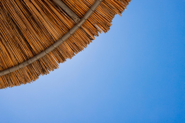 Photo bamboo parasols beach umbrellas with clear blue sky background on summer day