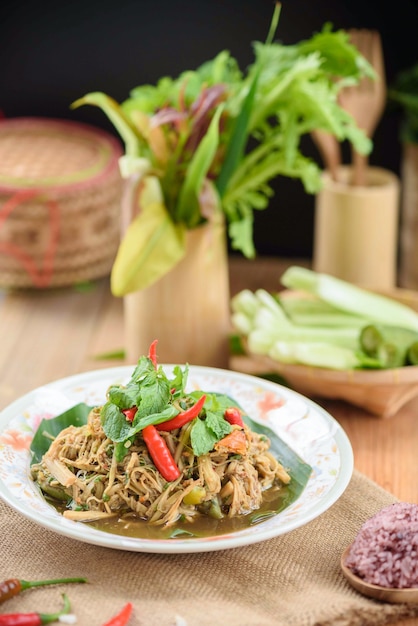 Bamboo shoot spicy salad with side dishes on wooden desk and black background