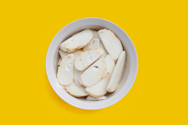 Bamboo shoots in white bowl on yellow background.