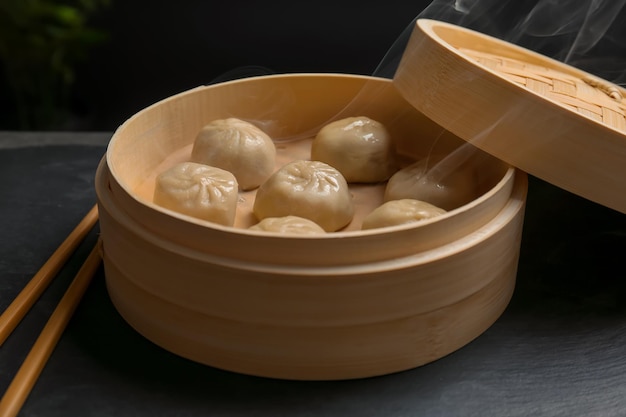 Bamboo steamer with tasty baozi dumplings on table