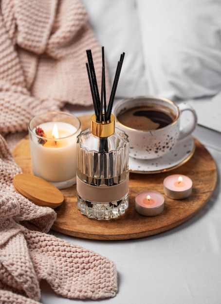 Bamboo sticks in bottle with scented candles and cup of coffee
