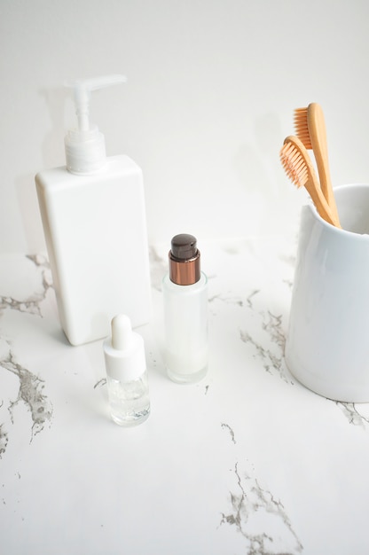 Bamboo toothbrush, face serums on a marble table