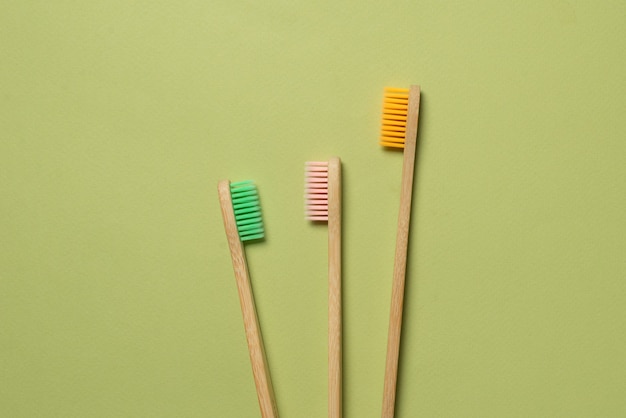 Bamboo toothbrush on a green background. Top view.