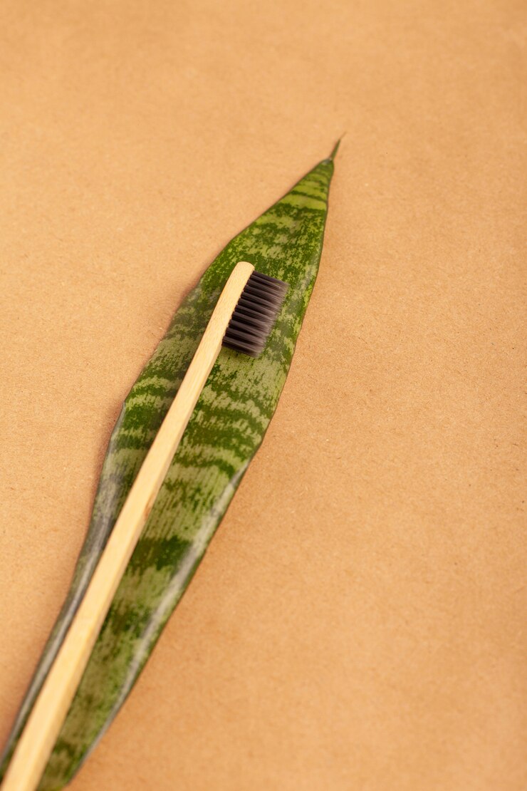 Bamboo toothbrush on a green sheet on a background of craft paper. Top view