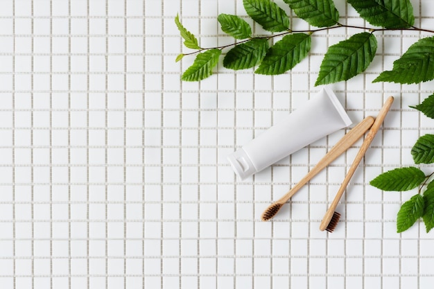 Bamboo toothbrush and toothpaste on white mosaic background top view Dental hygiene concept