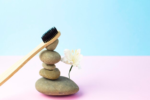 A bamboo toothbrush with black bristles balances on the rocks
