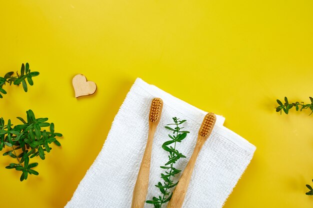 Bamboo toothbrushes and ear sticks green leaves on yellow paper