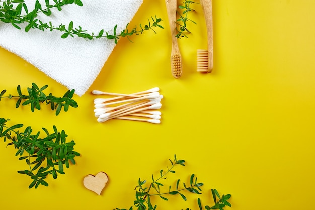 Bamboo toothbrushes and ear sticks with towel, and green leaves, eco-friendly, zero waste personal hygiene products, dental care concept