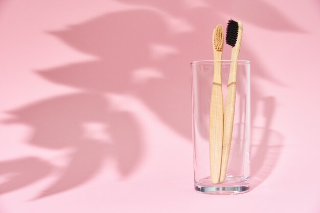 Bamboo toothbrushes in glass and leaf shadows