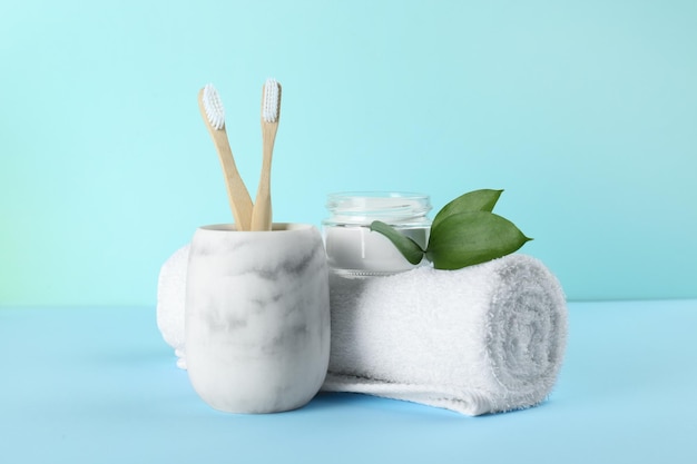 Bamboo toothbrushes towel and bowl of baking soda on light blue background