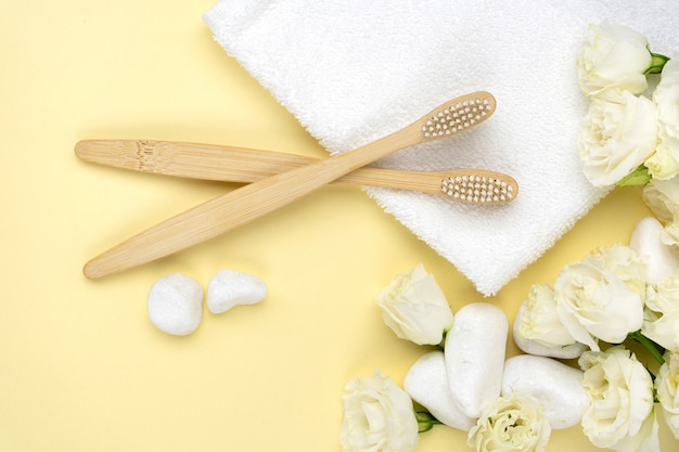 Bamboo toothbrushes with natural white bristles on a towel next to pebbles with a flower. the concept of zero waste, modern trends in conscious consumption. top view