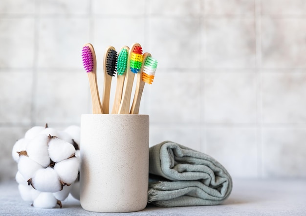 Photo bamboo toothbrushes with towel and cotton flowers biodegradable care products no plastic concepts