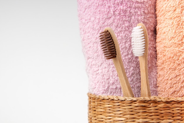 Bamboo toothbrushes with towels in wicker wooden basket. Spa, healthy lifestyle and ecology concept.