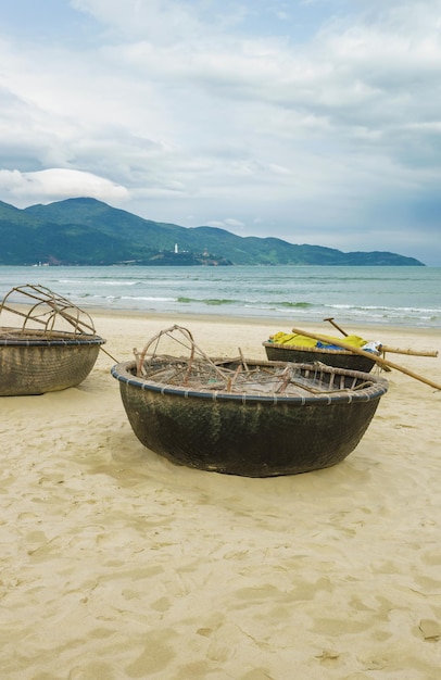 베트남 다낭의 차이나 비치에 있는 대나무 방수 원형 어선. 논 누옥 비치라고도 합니다. 배경에 남중국해와 대리석 산.