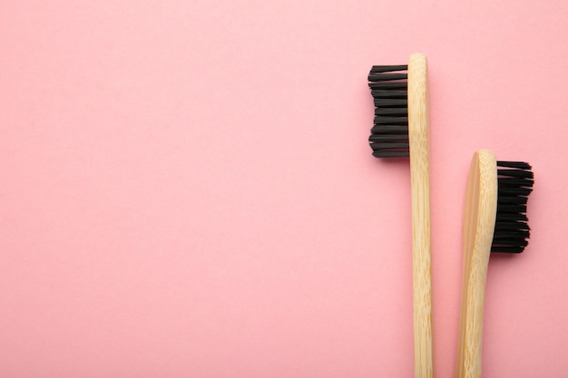 Bamboo wood toothbrush with black brush bristles on pink background