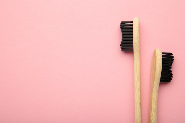 Spazzolino da denti in legno di bambù con setole nere su sfondo rosa