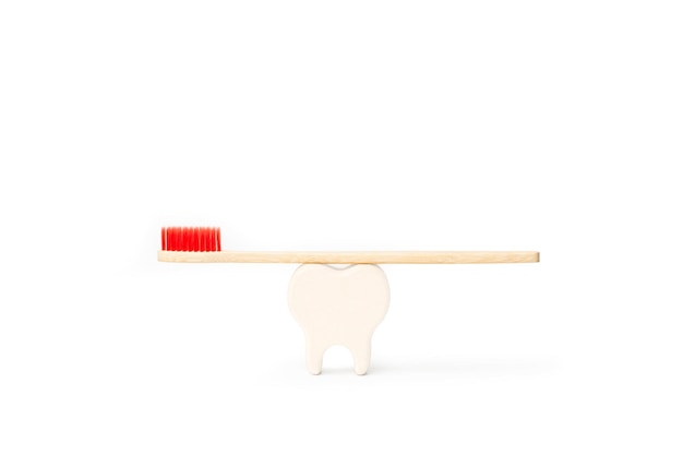 Фото Зубная щетка из бамбукового дерева с красной щетиной и белыми зубами на белом фоне с копией пространства