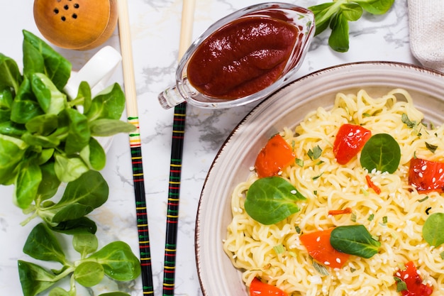 Bami met peper, slablaadjes en sesamzaadjes in een keramisch bord. Bovenaanzicht