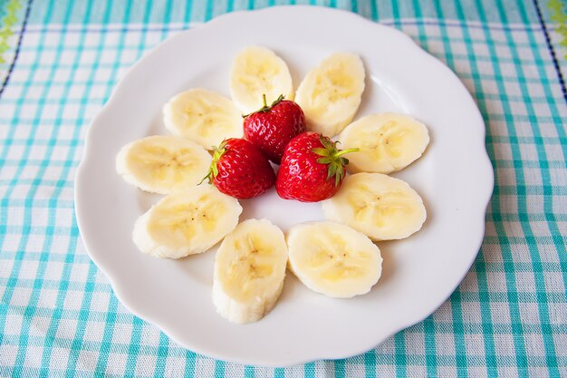 Banaan en aardbeien op een witte plaat en een kleurrijk servet