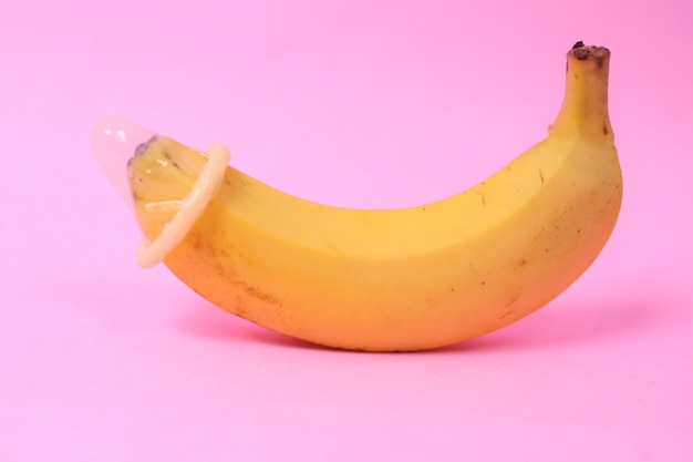 Banaan en anticonceptie geïsoleerd op roze achtergrond